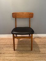 Front view of teak dining chair with black seat
