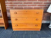 Front view showing three drawers, pulls, keyholes, overall finish