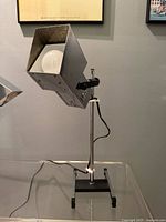 Lamp front view showing cube shade, bulb, chrome stem, black base