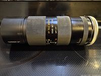 Side profile of Tamron SP 70-210 mm zoom lens showing branding, zoom and focus grips, aperture ring