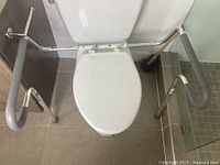Toilet safety frame mounted around toilet