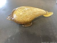 Left side view of amber glass whale paperweight