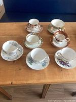 Seven teacup and saucer sets displayed on table