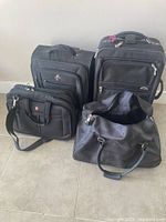 Four black luggage items: two upright suitcases, SwissGear briefcase, duffel bag