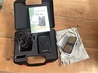 Open carrying case showing TENS 3000 unit, lead wires, electrode pads and manual