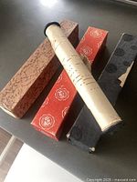 Four boxed player piano rolls with one roll partially unrolled showing perforations