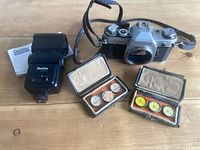 Canon AE-1 camera, Starblitz flash, two filter cases displayed