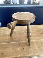 Full view of wooden milking stool on tabletop