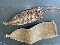 Two woven hanging art pieces laid flat on dark surface