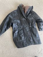 Full front view of black leather jacket laid flat
