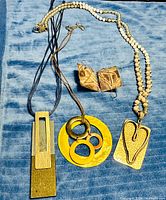 All three necklaces and earrings laid out on blue cloth