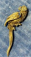 Full view of gold-tone bird brooch laying on fabric