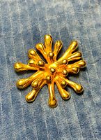 Front view of goldtone starburst brooch