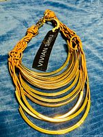 Full necklace showing tiered gold-tone bars, braided cords, brand tag