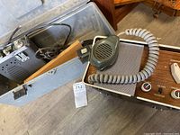 Open hard case with metal CB radio, second CB radio with wood-grain panel, microphone, cables