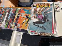 Stack of comics with Gambit and Booster Gold visible