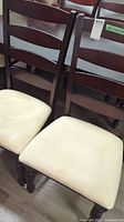 Front view of two chairs showing dark wood ladder backs and beige microfiber seats