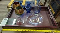 All items arranged on tray including tray, decanter, two blue vases, two gilt goblets, stack of coasters