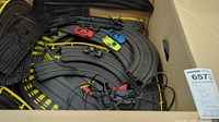 Box containing curved track sections, guardrails, wiring and four slot cars