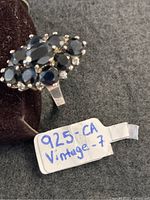Ring displayed on stand with handwritten tag noting 925 and size 7