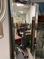 Front view of tall bevelled wall mirror within room setting