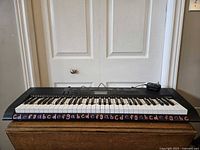 Front view of Casio 61-key keyboard on stand with adapter visible