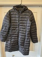 Front view of long hooded puffer jacket hung on hanger