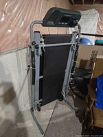 Folded Exerpeutic treadmill showing frame, belt, side handles and wheels