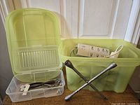 Overall lot showing green bin with lid, clear tool box, power bars, extension cords, tire wrench