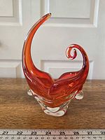 Front view of spike and curl orange red vase with ruler for scale