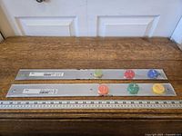 Two packaged IKEA magnetic bars with colorful magnets displayed on measuring surface
