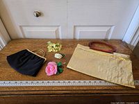 Group shot of both handbags and three floral pins with ruler for scale