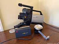 Hitachi video camera with accessory and Kodak Instamatic camera on table
