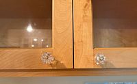 two clear glass hexagonal knobs mounted on wooden cabinet doors