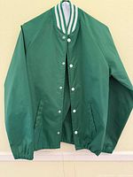 Front view of green stadium jacket showing snap closures, pockets and collar