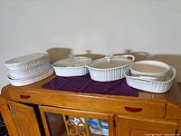Front view of entire set on cabinet showing four stacked bakers, two lidded casseroles and two small dishes