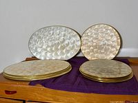 Two placemats displayed upright (one oval, one round) with stacks of additional placemats