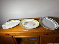 Three oval platters on cabinet showing size and patterns