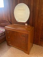full dresser with round mirror against wood panel wall