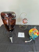 All four glass items grouped: face tealight holder, ornament on stand, feeder, stopper