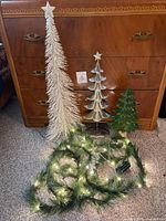 Three decorative trees and lighted garland with star ornaments displayed together