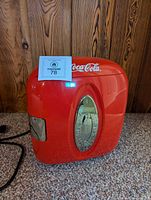 Front view of red Coca-Cola mini fridge powered on