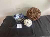 Group shot of glass pedestal bowl holding two ceramic balls, twig orb and cotton boll ornament