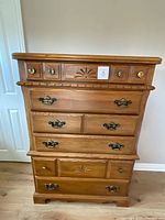 Front view showing honey oak tall dresser with six drawers and hardware