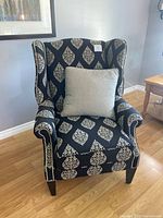 Full view of patterned wingback chair with accent pillow