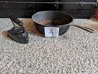 Pan and flat iron side by side on carpet