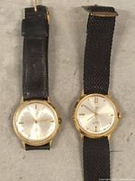 Two vintage wristwatches side by side showing dials and straps