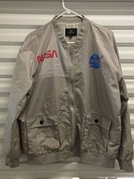 Front view of gray NASA bomber jacket on hanger showing full design