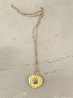 Full view of pendant watch and chain on flat surface