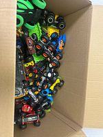 Box filled with assorted monster trucks and cars